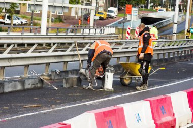 Arnhem, Hollanda - 4 Kasım 2022: Turuncu güvenlik yeleği giyen iki kişi tarafından sokakta inşaat faaliyetleri