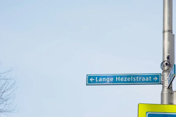 Blue street name sign of Lange Hezelstraat with a clear blue sky in the background in Nijmegen in the Netherlands