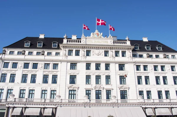 stock image Copenhagen, Denmark - April 6, 2023: White facade of Hotel d'Angleterre with danish flags on top in the center of Copenhegen with a clear blue sky