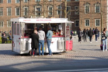 Kopenhag, Danimarka - 9 Nisan 2023: Kopenhag 'ın merkezinde geleneksel bir sosisli arabasının yanında bekleyen müşteriler