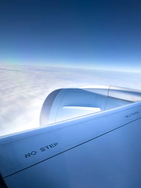 窓から見える青い空に対して風光明媚な雲の上を飛ぶ飛行機のジェットエンジンのトリミングされたイメージ — ストック写真