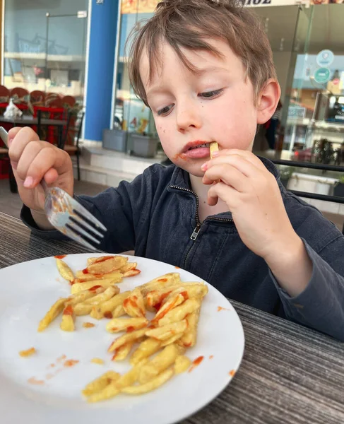 Caucásico Lindo Chico Sosteniendo Tenedor Comer Papas Fritas Con Mano —  Fotos de Stock