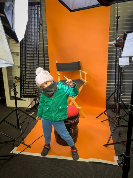 在演播室里 全长的男孩穿着温暖的衣服 在橙色的背景下摆出姿势和姿势 — 图库照片