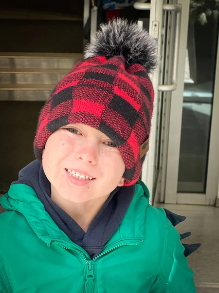 可爱的高加索男孩头戴针织帽子 身穿冬季外套 与人造建筑相抗衡的特写 — 图库照片