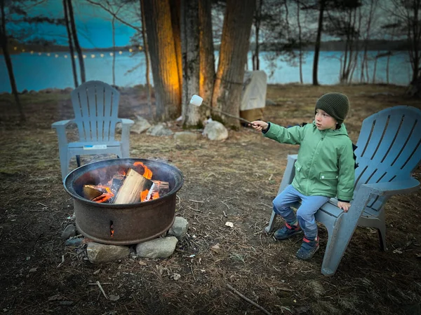 Pojke Varma Kläder Stekande Marshmallow Över Lägereld Sittande Adirondack Stol — Stockfoto
