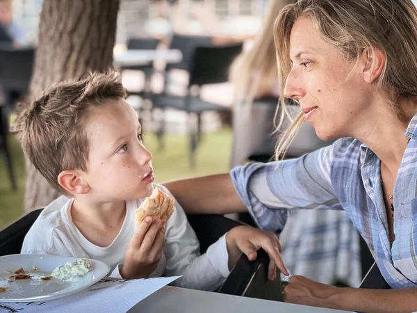 Caucásico Madre Mirando Lindo Hijo Comer Sándwich Mientras Sentado Silla —  Fotos de Stock