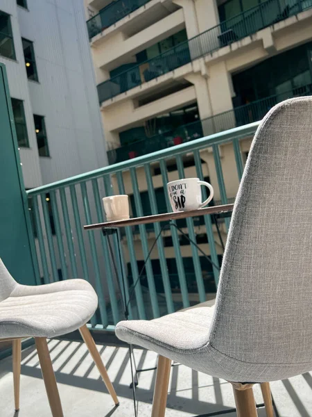 晴れた日にはバルコニーで手すりや灰色の空の椅子によってテーブルの上にコーヒーカップの低角度ビュー — ストック写真