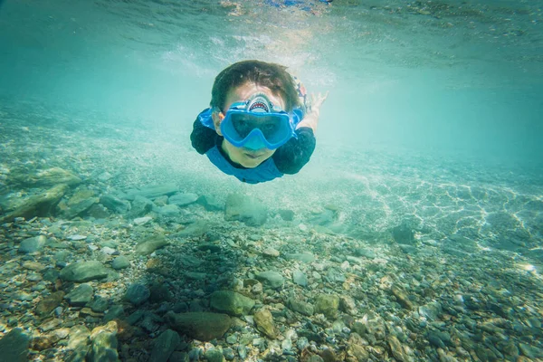 stock image Portrait of carefree boy wearing blue swimming goggles and diving underwater over ocean floor in sea