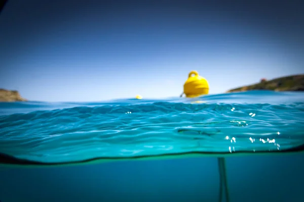 晴れた日には澄んだ青空と海の水面に浮かぶ黄色のブイ ストック写真