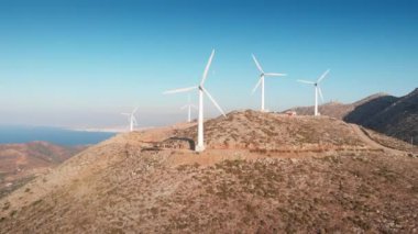 Dağdaki büyük rüzgar türbinleri ve güneşli bir günde berrak mavi gökyüzüne bakan görkemli manzaralar.