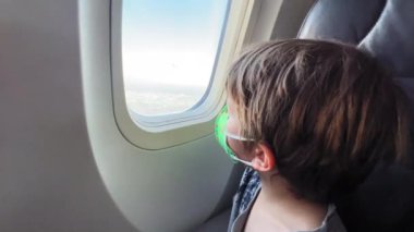 boy in the mask sitting in the window of the airplane