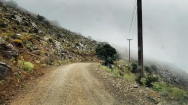 Dağların tepesinde hareket eden bulutlarla dolu bir yol.