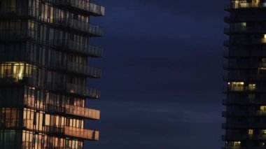 Gece boyunca mavi bulutlu gökyüzüne karşı aydınlatılmış modern gökdelenler.