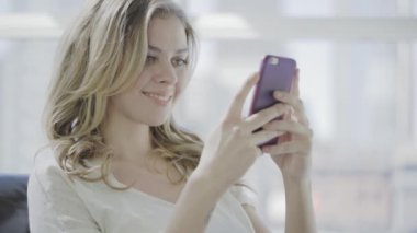 Ofiste cep telefonu kullanan genç bir kadın.