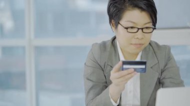 İş yerinde kredi kartıyla çalışan Asyalı iş kadını