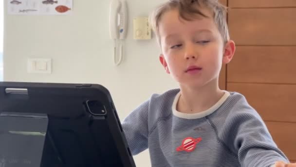 Söt Vit Pojke Tittar Uppmärksamt Digital Tablett Bordet Medan Studerar — Stockvideo