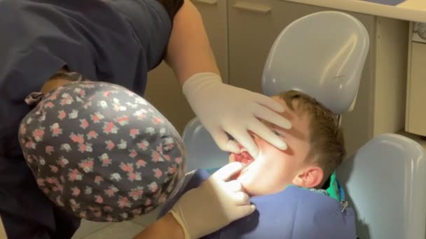 歯医者は診療所で少年患者の歯を調べる — ストック動画