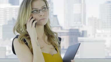 Genç sarışın iş kadını cep telefonuyla konuşuyor. 