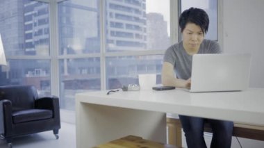 Masada dizüstü bilgisayar kullanan Asyalı kadın.