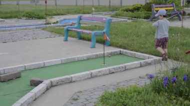 Küçük çocuk mini golf oynuyor.