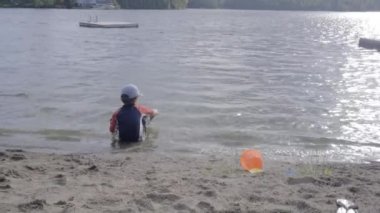 Küçük çocuk kıyıya yakın gölde oynuyor.