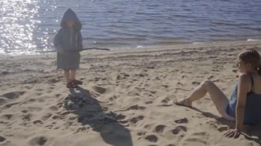 Anne ve oğlu yazın sahilde göl kenarında dinleniyorlar.