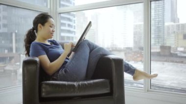 Evinde dijital tablet kullanan mutlu Asyalı kadın.