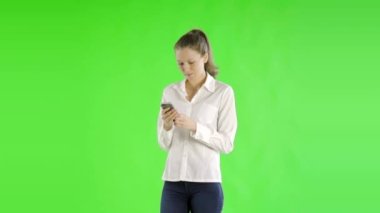 Genç ve güzel iş kadını yeşil ekranda telefonla mesajlaşıyor.