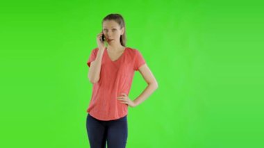 Spor kıyafetleri giyen genç ve güzel bir kadın yeşil ekranda telefonla konuşuyor.