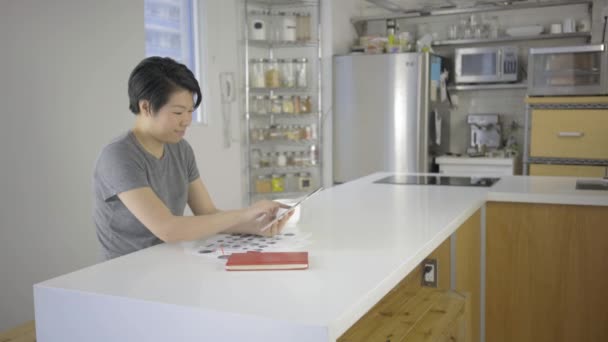 Азиатка Помощью Цифрового Планшета Документами Столе Кухне — стоковое видео