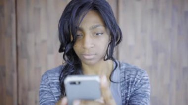 Afro Afrikalı kadın akıllı telefonuyla evde.