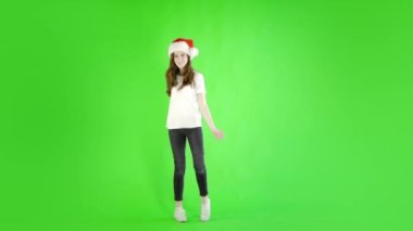 Beyaz kadın, günlük kot pantolon giyiyor. Stüdyonun karşısında Noel Baba şapkası giyiyor. 