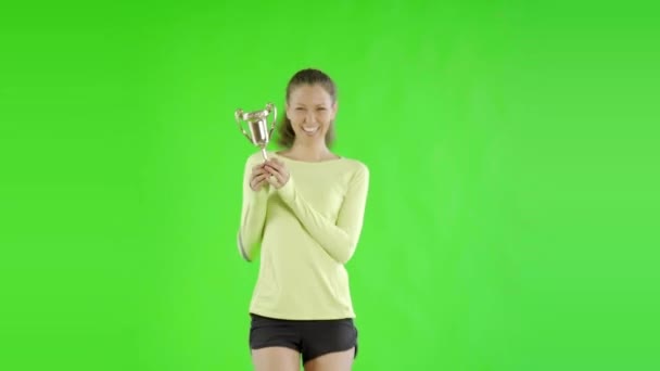 年轻漂亮的女人穿着运动服 绿色荧幕上挂着奖杯 — 图库视频影像