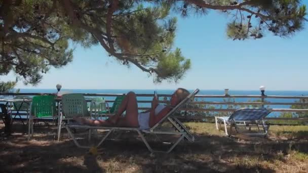 Жінка Лежить Стільці Телефоном Оточенні Скелі Красивого Моря — стокове відео