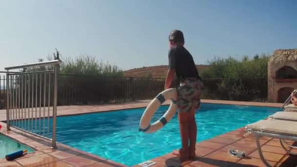 暑假期间带着孩子在游泳池边的松懈父母 — 图库视频影像