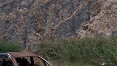 Yol kenarındaki eski bozuk araba kaya oluşumlarına karşı