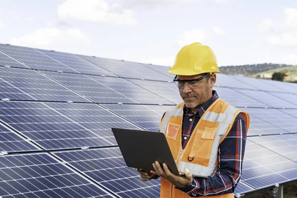 Portrait of male manager engineer in safety helmet checking with computer an operation of solar panel system at solar station