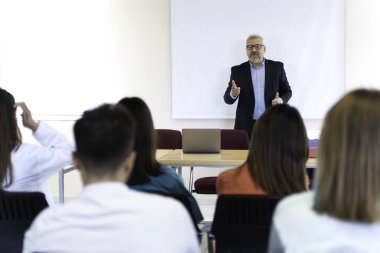 Bir grup insan dizüstü bilgisayarları ve projektörleri olan bir masada oturuyor. Büyük olasılıkla bir proje veya sunumu tartışıyorlar