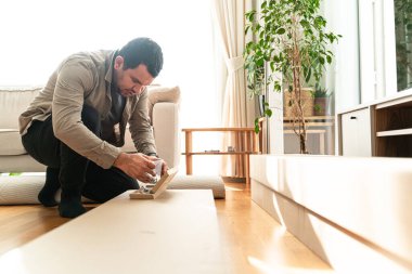 Kendi kendini monte etmek için mobilya montajı yapan yeni bir evde çalışan bir adam. Profesyonel Mobilya Alanı İşçi Birliği Rafı. Profesyonel Tamirci, Yeni Ev 'e taşınan insanlara yardım ediyor..
