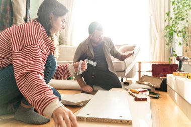 Genç bir çift evlerinde mobilya montajı yaparak evlendi. Elinde tornavida ve kullanma kılavuzunu takip edecek aletlerle. Becerikli çift. Sahibi onlar. Yeni ev, yeni mobilyalar.