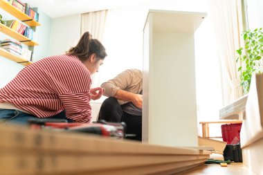 Genç bir çift evlerinde mobilya montajı yaparak evlendi. Elinde tornavida ve kullanma kılavuzunu takip edecek aletlerle. Becerikli çift. Sahibi onlar. Yeni ev, yeni mobilyalar.