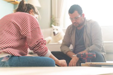 Genç bir çift evlerinde mobilya montajı yaparak evlendi. Elinde tornavida ve kullanma kılavuzunu takip edecek aletlerle. Becerikli çift. Sahibi onlar. Yeni ev, yeni mobilyalar.