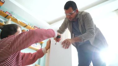 Mutlu çift bir takım olarak mobilya birleştirir, kız talimatları okur ve çocuk bir matkap ile vida sıkılaştırır. Yeni daire içine taşıma, Çift raf birleştirin.