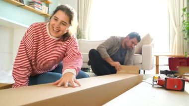 Mutlu çift bir takım olarak mobilya birleştirir, kız talimatları okur ve çocuk bir matkap ile vida sıkılaştırır. Yeni daire içine taşıma, Çift raf birleştirin.