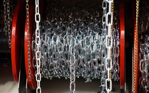 Long silver metal chains wound on a reel and displayed for sale