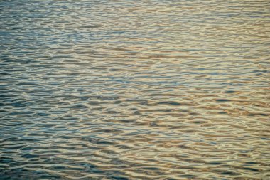 Dalgalı okyanus yüzeyinin artan karışık ışık renkleri soyut bir illüstrasyon gibi görünüyor.