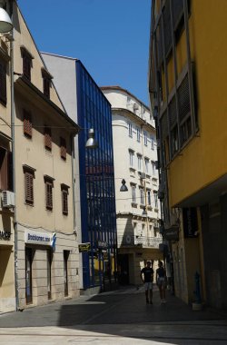 Rijeka, Hırvatistan, 9 Temmuz 2023. Şehir caddesinde büyük binalar arasında geçiş