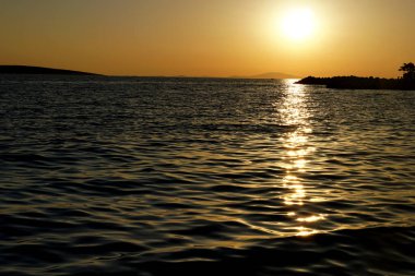 Hırvatistan 'ın deniz kıyısında karanlık turuncu gün batımı ve kirlenmemiş çevre