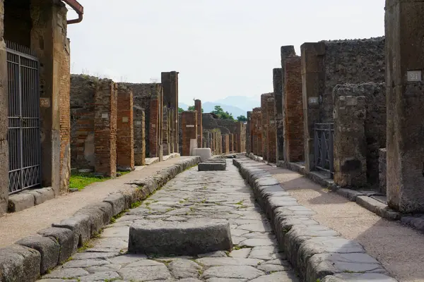 İtalya, Pompeii, 14 Haziran 2023. Pompeii 'nin turistik bölgesinde duvarları ve kalıntıları olan taştan bir sokak.