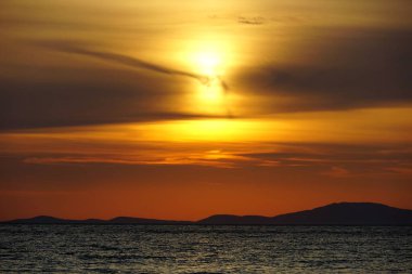 Gün batımında ateşli, dramatik turuncu gökyüzü ile dalgalı deniz yüzeyi